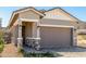 Inviting single-Gathering home featuring a covered front porch, neutral stucco, a brick driveway, and a two-car garage at 5678 N 205Th Ln, Buckeye, AZ 85396