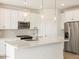 Modern kitchen with white cabinets, quartz countertops, stainless steel appliances, and pendant lighting at 16025 W Cottontail Ln, Surprise, AZ 85387