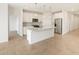 Modern kitchen boasts stainless steel appliances, a large island with pendant lights, and white cabinets at 16025 W Cottontail Ln, Surprise, AZ 85387