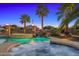 Stunning pool area with a waterfall feature and spa, illuminated against the twilight sky at 7205 W Fallen Leaf Ln, Peoria, AZ 85383