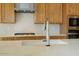 Close-up view of kitchen with stainless faucet and quartz countertops, complemented by modern appliances and wooden cabinets at 33337 N Maverick Mountain Trl, Queen Creek, AZ 85144