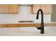 Close-up of a kitchen island with granite countertops, wooden cabinets, and a black faucet at 4799 W Flat Iron Ct, Queen Creek, AZ 85144