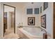 Bathroom featuring a soaking tub beneath clerestory windows, tile surround, and adjacent glass-enclosed shower at 9216 E Sky Line Dr, Scottsdale, AZ 85262