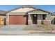 Single-story home with brown garage door, stone accents, and landscaping at 16014 W Cottontail Ln, Surprise, AZ 85387