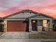 Charming house with a brown garage door and stone accents at 16014 W Cottontail Ln, Surprise, AZ 85387