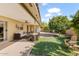 Comfortable covered patio with seating area overlooking lush backyard with artificial turf and mature trees at 4019 E Calypso Ave, Mesa, AZ 85206