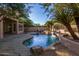 Private backyard retreat with a freeform pool, waterfall feature, and covered patio area at 11568 E Whispering Wind Dr, Scottsdale, AZ 85255