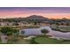 Scenic aerial view of a golf course community with a tranquil lake and mountain backdrop at sunset at 6429 S Honor Ct, Gilbert, AZ 85298