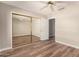 Neutral bedroom with wood-look floors, ceiling fan and mirrored closet doors at 13335 W Broken Arrow Dr, Sun City West, AZ 85375