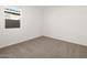 A vacant carpeted bedroom with a large window letting in lots of light at 36944 W Prado St, Maricopa, AZ 85138