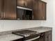 Close up of kitchen with granite countertops, stainless steel appliances, and dark wood cabinets at 36944 W Prado St, Maricopa, AZ 85138
