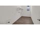 Bright laundry room with wood-look tile flooring, open shelving, and natural light at 17134 W Hackamore Dr, Surprise, AZ 85387