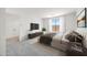 A staged bedroom with a bed, side tables, TV, window with curtains, and interior door at 25137 N 171St Ave, Surprise, AZ 85387