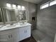 This bathroom features a walk in shower and double sinks with white cabinets at 15075 W Amelia Dr, Goodyear, AZ 85395