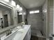 Bathroom with double sinks, modern mirrors, and a tiled walk-in shower at 15075 W Amelia Dr, Goodyear, AZ 85395