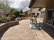 A spacious covered patio with decorative concrete flooring and a small table with two chairs overlooks a landscaped backyard at 15075 W Amelia Dr, Goodyear, AZ 85395