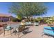 An open patio with various seating arrangements surrounded by a green tree and lush desert landscaping at 20394 N Coronado Way, Surprise, AZ 85374