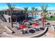 Community pool area with a two-story building, tables, chairs, umbrellas, and palm trees at 8700 E University Dr # 2020, Mesa, AZ 85207