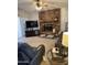 Cozy living room featuring a brick fireplace, ceiling fan, comfortable leather seating, and neutral carpeting at 402 W Grandview Rd, Phoenix, AZ 85023
