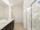 Bathroom featuring double sinks, dark cabinets, tiled floor, and a glass-enclosed shower at 16039 W Desert Hollow Dr, Surprise, AZ 85379