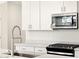 Close up of modern kitchen featuring stainless steel appliances, white cabinets, and quartz countertops at 16037 W Desert Hollow Dr, Surprise, AZ 85387