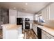 Well-lit kitchen showcases white cabinetry, black appliances, breakfast bar, and wood-look flooring at 22264 N Kingston Dr, Maricopa, AZ 85138