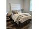 Stylish bedroom showcases a tall upholstered headboard with neutral bedding and dark wood floors, offering a relaxing atmosphere at 10637 W Eucalyptus Rd, Peoria, AZ 85383