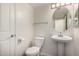 Bright powder room featuring a pedestal sink, oval mirror, and convenient toilet at 1926 E Siesta Ln, Phoenix, AZ 85024