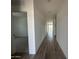 An open hallway featuring stylish wood-look floors, white walls, and access to other rooms in the home at 46963 W Coe St, Maricopa, AZ 85139