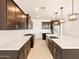 Spacious kitchen with stainless steel appliances, dark wood cabinets, quartz countertop island, and wood floors at 4994 W Hunter Trl, San Tan Valley, AZ 85144
