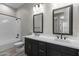 Modern bathroom with dual sinks, dark cabinetry, gold hardware, and tiled shower at 32513 N 135Th Dr, Peoria, AZ 85383