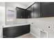 Laundry room boasts storage with overhead cabinets and sink in a dark finish at 32513 N 135Th Dr, Peoria, AZ 85383