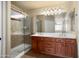 Bathroom featuring a double vanity, framed mirror and a tiled shower with glass door at 2606 N 159Th Dr, Goodyear, AZ 85395