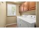 Bright laundry room with wooden cabinets, washer and dryer at 2606 N 159Th Dr, Goodyear, AZ 85395