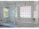 Luxurious bathroom featuring a glass-enclosed shower and a separate soaking tub beneath a window at 1416 E Sapium Way, Phoenix, AZ 85048