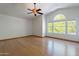 Spacious bedroom with wood floors, a ceiling fan, and large windows offering views of lush greenery at 1416 E Sapium Way, Phoenix, AZ 85048