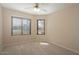 Cozy bedroom with carpet, ceiling fan, and two bright windows at 8464 W Royal Blackheath Dr, Arizona City, AZ 85123