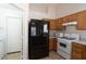 Well lit kitchen with wooden cabinets, black fridge, and white appliances at 8464 W Royal Blackheath Dr, Arizona City, AZ 85123