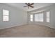 Spacious bedroom with neutral carpet, ceiling fan, and abundant natural light from multiple windows at 32030 N 20Th Ln, Phoenix, AZ 85085