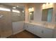 Bathroom featuring double sinks, white cabinets, and a marble-tiled shower at 1042 W Ridge Rd, Apache Junction, AZ 85120