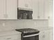 Close-up of a kitchen featuring a stainless steel oven, marble backsplash, and white shaker style cabinets at 4937 W Hunter Trl, San Tan Valley, AZ 85144