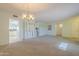 Spacious living room featuring neutral carpet, chandelier and a large window for natural light at 12442 W Marble Dr, Sun City West, AZ 85375