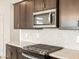 Modern kitchen featuring stainless steel appliances, mosaic backsplash, and dark cabinetry at 16017 W Cottontail Ln, Surprise, AZ 85387