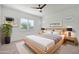 Bright bedroom with neutral colors, ceiling fan, bedside tables and an accent plant at 17917 W Amberwood Dr, Goodyear, AZ 85338
