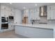 Modern kitchen with stainless steel hood, island sink, and gray cabinetry at 1300 E Penedes Dr, Gilbert, AZ 85298