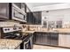 Galley style kitchen with granite countertops, stainless appliances and dark cabinetry at 22364 N 67Th Dr, Glendale, AZ 85310