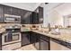 Galley style kitchen with granite countertops, stainless appliances and dark cabinetry at 22364 N 67Th Dr, Glendale, AZ 85310
