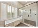 Bright bathroom showcasing a soaking tub by the window with plantation shutters and a glass shower at 7928 E Parkview Ln, Scottsdale, AZ 85255