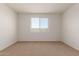 Empty bedroom with plush carpet, a window for natural light, and neutral paint at 18197 W Cielo Grande Ave, Surprise, AZ 85387