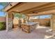 A well-appointed outdoor kitchen features a built-in grill, counter space, and seating beneath a covered patio at 4301 E Taurus Pl, Chandler, AZ 85249